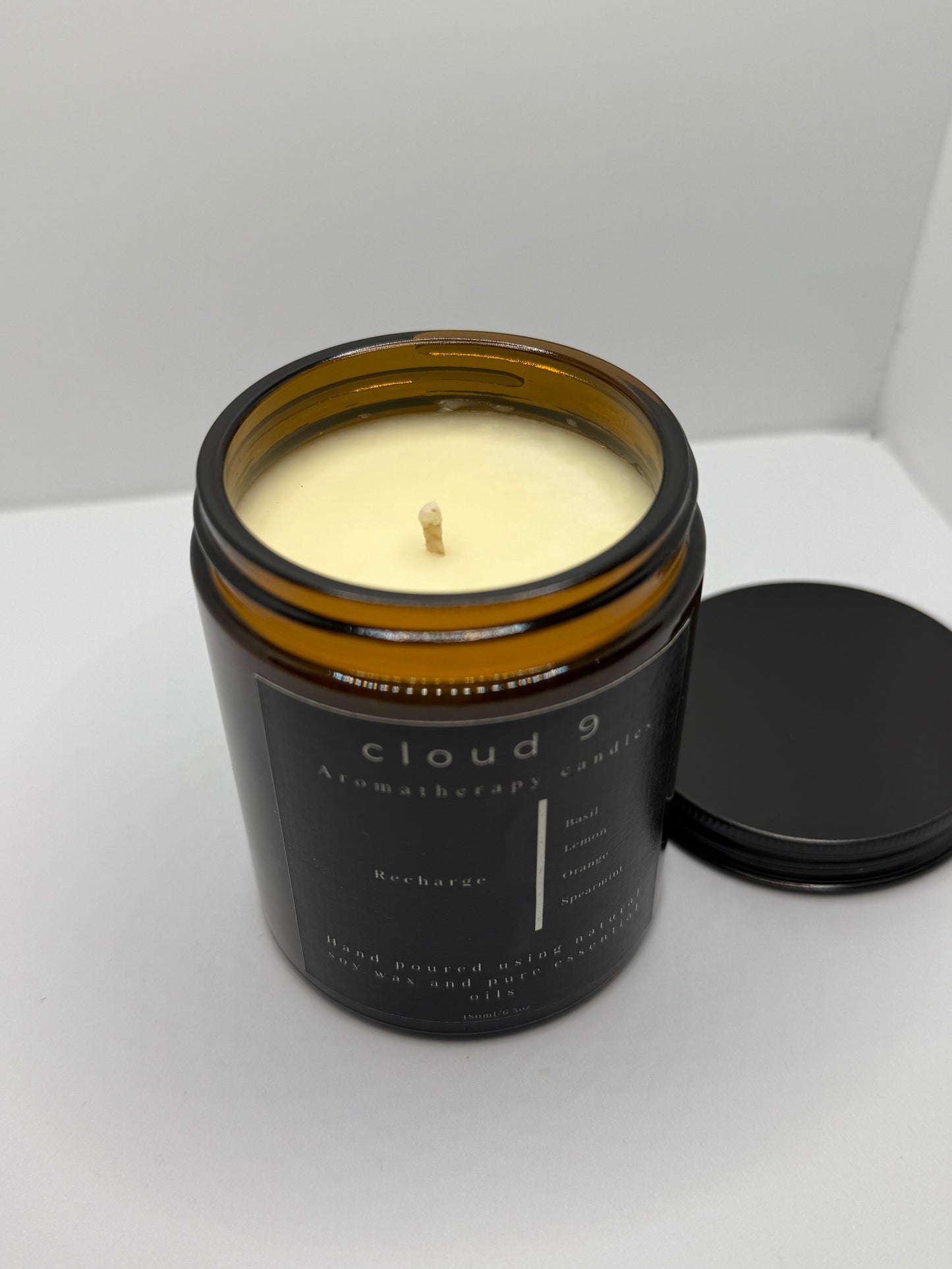 The ‘Recharge’ candle lit beside a neutral-toned mug in a calm home-office environment, suggesting a moment of focused clarity and refreshment with its energizing aroma.