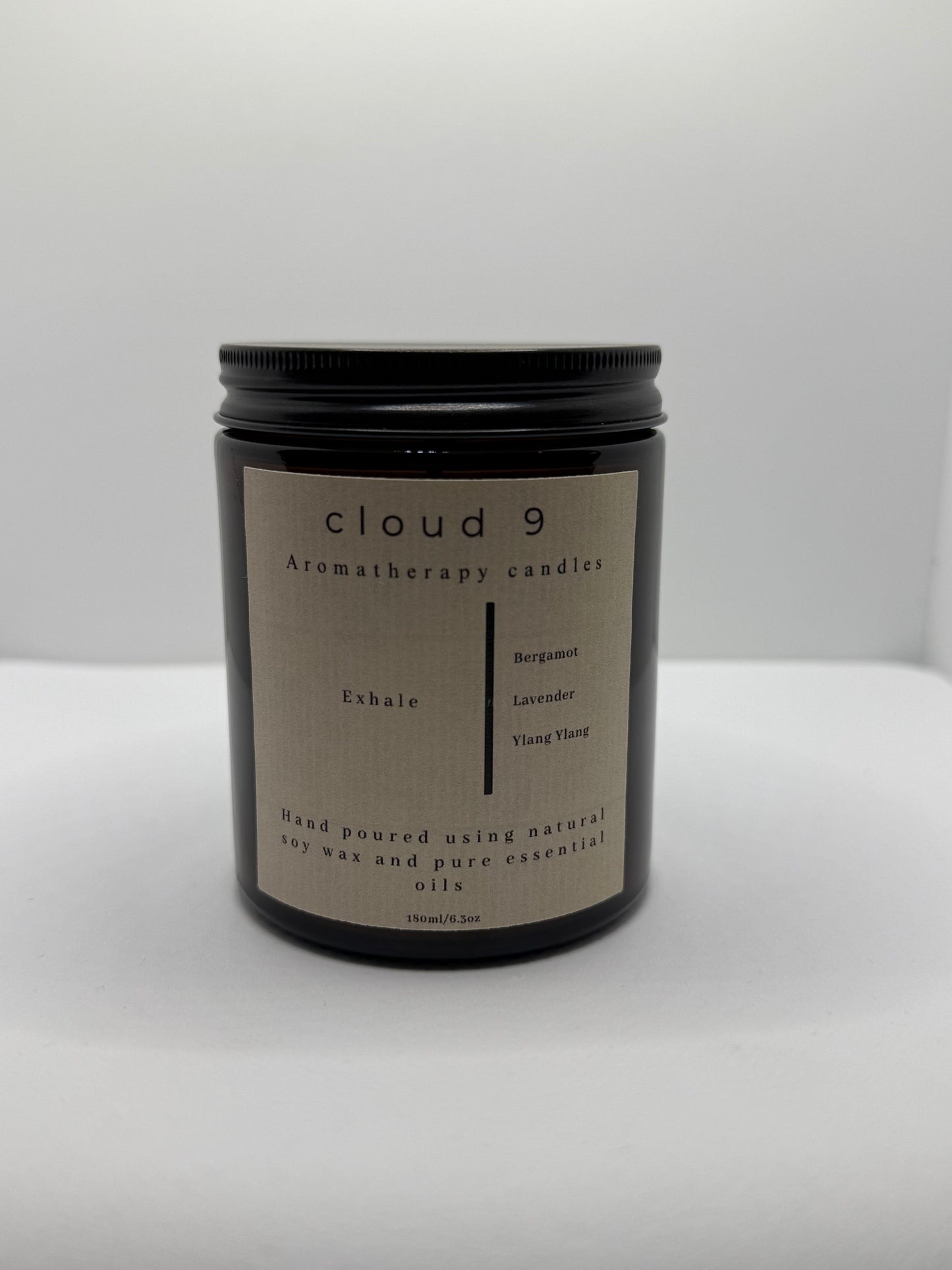 Amber ‘Exhale’ aromatherapy candle with decorative green foliage beside it, highlighting the candle’s calming scent profile of lavender and bergamot
